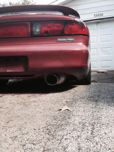 1995 Ford Probe - The rear passenger side of a red MazdaSpeed GT is shown parked in front of a white garage door with the house number "25316" visible. A lea…