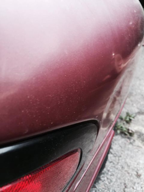 1995 Ford Probe - A close-up, angled view of the rear passenger side of a dark red metallic car, showing part of the taillight and the curved body panel abov…