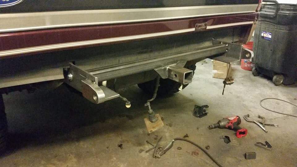 Custom rear bumper with hitch receiver on a dark red SUV, with tools on the floor.