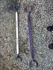 1995 Ford Probe - Two long, narrow objects with claw-like ends and a series of holes along their length are laid on a gravel surface. One object is white and…