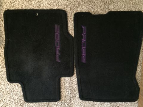 1995 Ford Probe - Two black floor mats with purple embroidered "PROBE" text are laid out on a carpeted surface. The mats appear to be for a car.