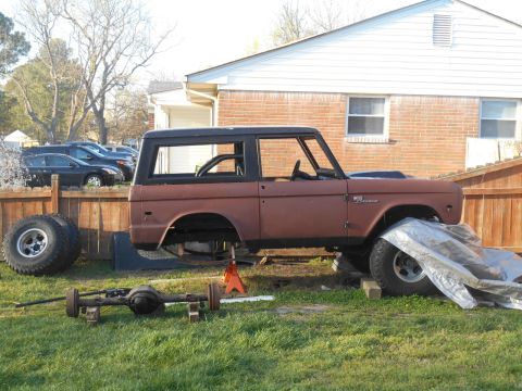 1972 Ford Bronco - A disassembled 1972 Ford Bronco is shown outdoors, with its body on jack stands and a separate axle assembly in the foreground. The vehicle…