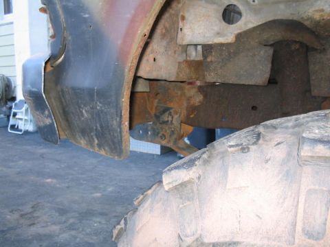 1979 Ford Bronco - The underside of a vehicle shows significant rust on the frame and a large tire.