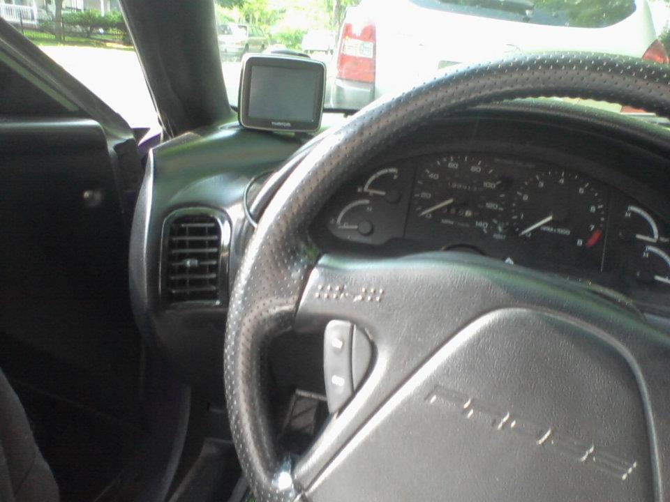 Interior of a car showing steering wheel, dashboard, gauges, and GPS unit.