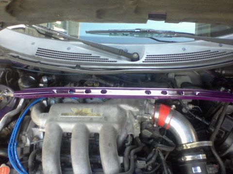 1995 Ford Probe - The image shows a close-up view of a car's engine bay, focusing on the intake manifold and a purple strut tower brace. Blue spark plug wire…