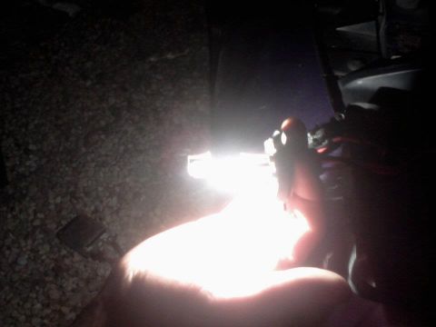 1995 Ford Probe - A hand is holding a bright LED light bulb in front of a dark background with gravel and some vehicle parts visible.