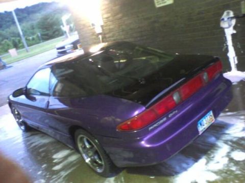 1995 Ford Probe - A purple 1995 Ford Probe is being washed at an outdoor car wash. The car is a coupe and is viewed from the rear quarter angle.