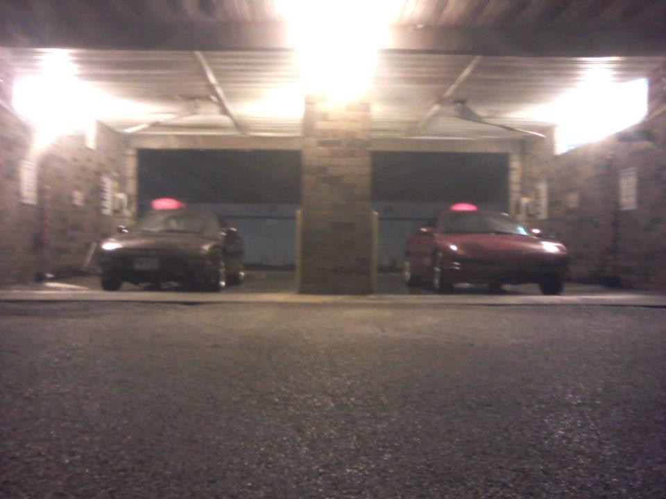 Two red sports cars parked in a garage.