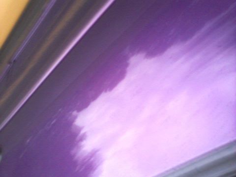 1995 Ford Probe - A close-up, angled view of a purple metallic car door with a lighter, cloudy reflection on its surface. The edge of the door and a darker t…