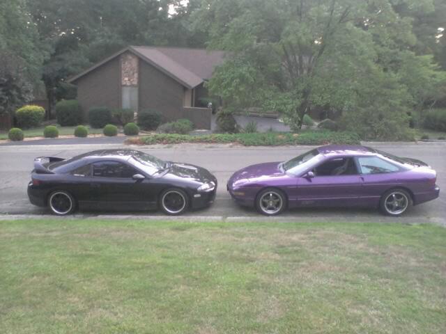 Two sports coupes, one black and one purple, parked next to each other.