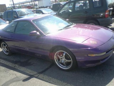 1995 Ford Probe - A purple 1995 Ford Probe is parked in a lot with other vehicles visible.