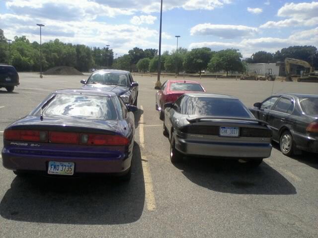 Two Ford Probe cars, one purple and one silver, parked in a lot. The purple one has 'PROBE 2.5' on the rear. The silver one has license plate 'CHK 3017'