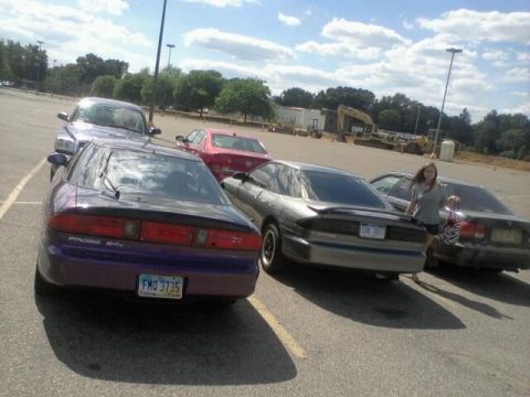 1995 Ford Probe - A purple car with a spoiler is parked in a lot, with other vehicles and construction equipment in the background.