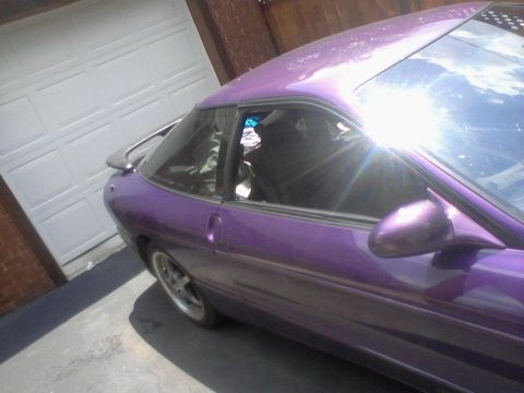 1995 Ford Probe - A purple 1995 Ford Probe is seen from a three-quarter front angle, parked in front of a garage.