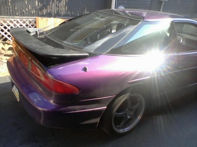 Purple sports coupe with a spoiler, seen from the rear