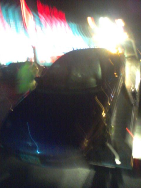 1995 Ford Probe - Blurry night shot of a car's hood and windshield with colorful lights streaking across.
