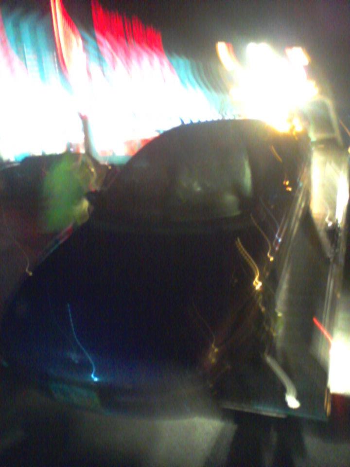 Car hood and windshield at night with blurry colorful lights reflecting