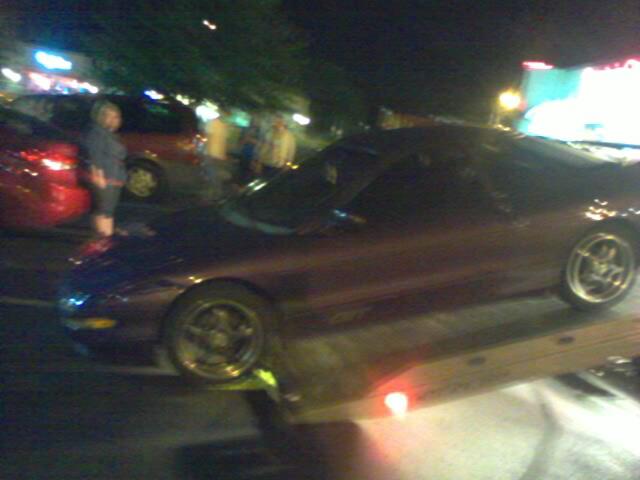 1995 Ford Probe being loaded onto a tow truck at night
