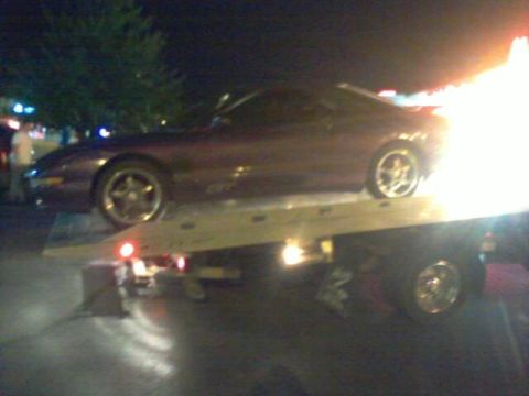 1995 Ford Probe - A purple 1995 Ford Probe is loaded onto a tow truck at night.