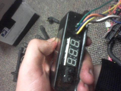 1995 Ford Probe - A hand holds a digital gauge with visible wires and two buttons, suggesting an aftermarket or custom installation.