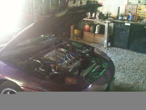 1995 Ford Probe - The engine bay of a car is visible with the hood raised in a workshop.