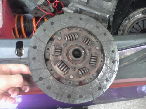 1995 Ford Probe - A close-up view of a car's clutch disc and pressure plate assembly, with a hand visible in the lower left corner. The vehicle appears to be…
