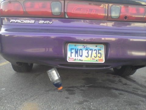1995 Ford Probe - The rear bumper of a purple Ford Probe is shown, with a license plate reading "FMQ 3735" and a Gatorade bottle lying on the ground beneath…