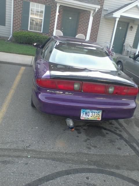 1995 Ford Probe - The rear view of a purple 1995 Ford Probe is shown parked in a parking lot. A plastic bottle is attached to the exhaust pipe.