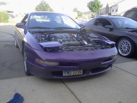 1995 Ford Probe - A modified purple 1995 Ford Probe is parked in a driveway with its hood open, revealing the engine bay. A dark-colored car is parked behind…