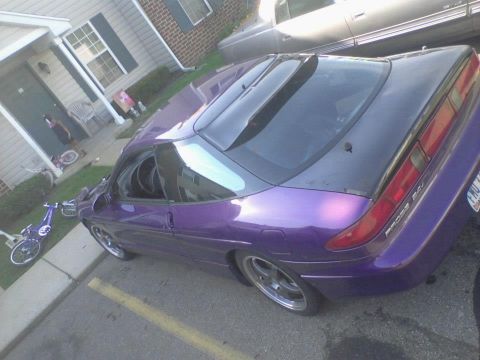 1995 Ford Probe - A modified purple 1995 Ford Probe is parked in a driveway next to a building. The car has a black roof and a custom spoiler on the rear win…