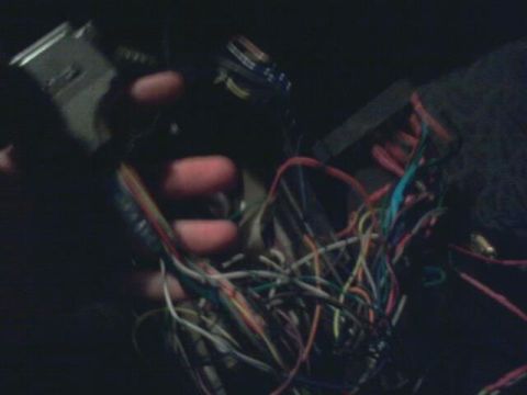 1995 Ford Probe - A hand holds a bundle of colorful wires connected to a silver electronic component, likely part of a vehicle's wiring harness.