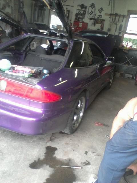 1995 Ford Probe - A purple 1995 Ford Probe is parked in a garage with its hood and trunk open, revealing the interior and engine bay. Tools and parts are sca…