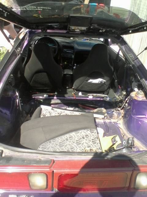 1995 Ford Probe - The interior of a purple 1995 Ford Probe is shown with the roof open and the rear seats removed. A patterned seat cushion is visible in the…