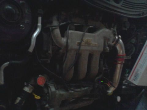 1995 Ford Probe - A close-up view of a car engine, focusing on the intake manifold and various hoses and wiring. The engine bay appears dark and somewhat clu…