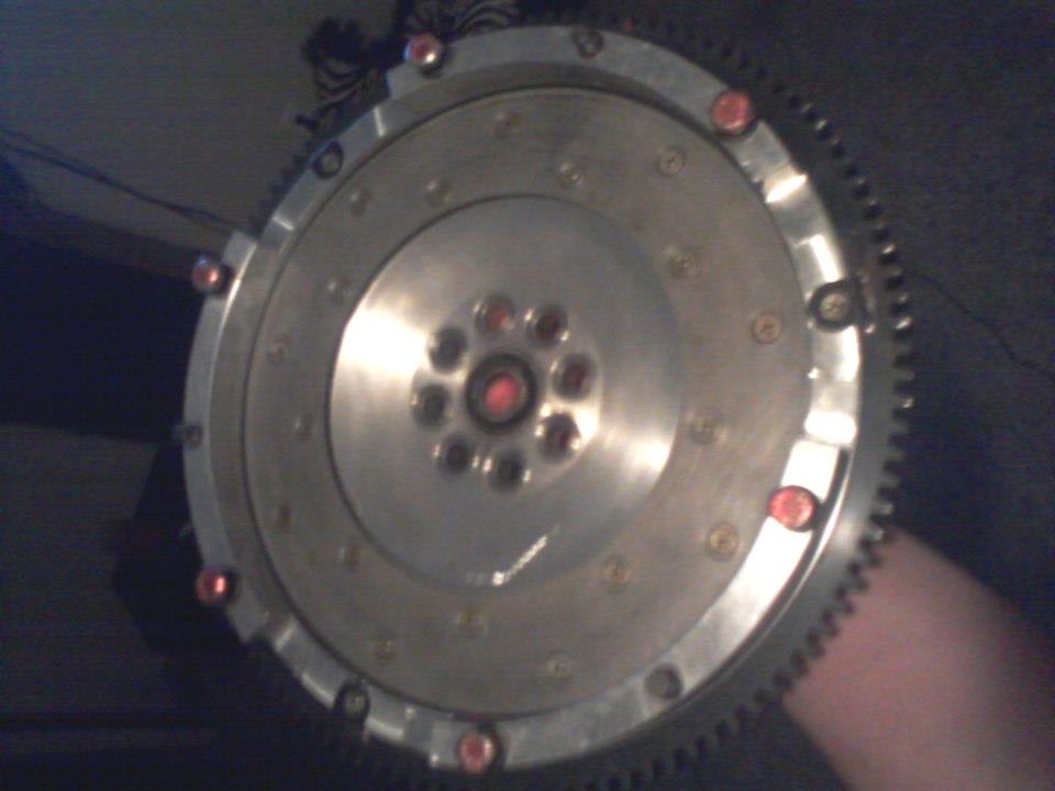 Silver flywheel with teeth and red bolts