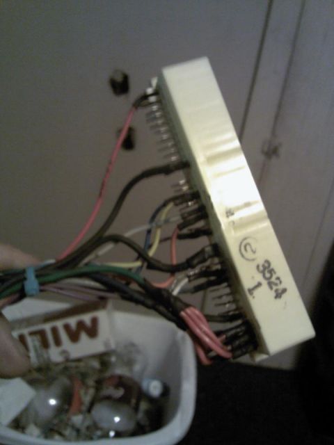 1995 Ford Probe - A close-up shot of a bundle of wires connected to a white electrical connector. The connector has some text and numbers printed on it, incl…