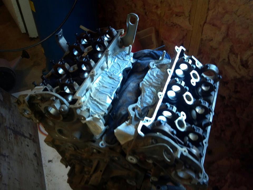 Disassembled V-engine block with valve covers in a workshop.