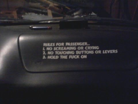 1995 Ford Probe - A close-up view of a car's dashboard shows a black plastic panel with white text listing "RULES FOR PASSENGER..". The rules state: 1. NO SC…