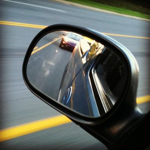 1995 Ford Probe - A side mirror reflects a purple car driving on a road with yellow lane lines. The reflection also shows a portion of the car the mirror is…