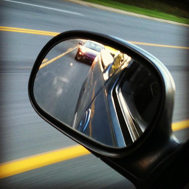Reflection of a purple car in a car's side mirror.