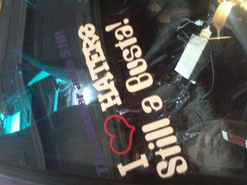 1995 Ford Probe - A close-up shot of a car's rear window shows white text decals. The decals read "Haters" and "I Still a Busta!", with a heart graphic and s…