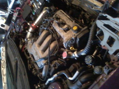 1995 Ford Probe - A close-up, overhead view of a modified car engine bay. Visible components include intake piping, the engine block, hoses, and wiring.