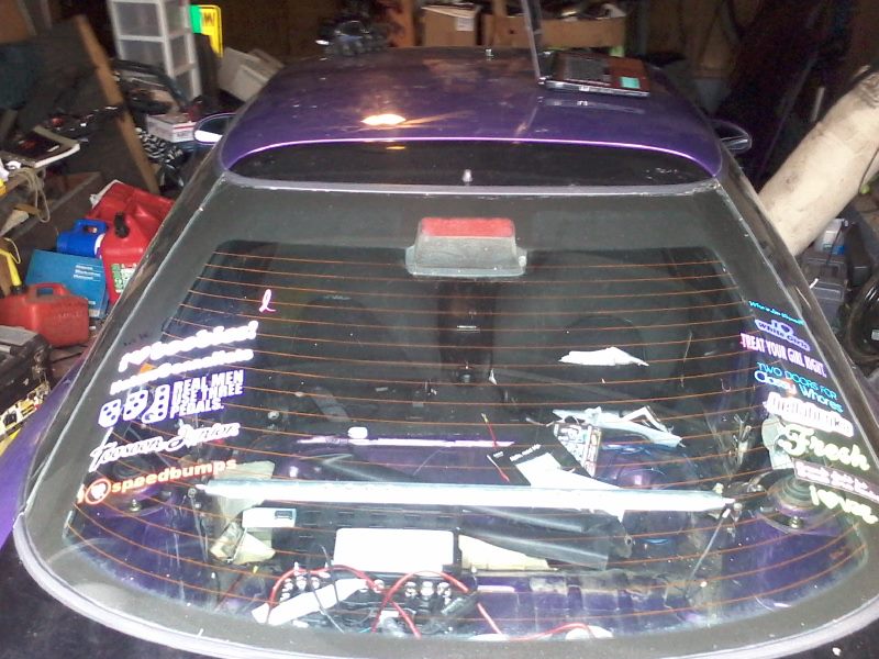 Purple hatchback rear window with stickers and visible interior wiring.