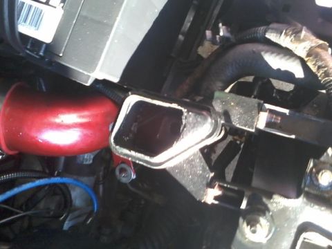 1995 Ford Probe - A close-up view of a red intake pipe connected to a black metal component with a damaged opening. Various hoses and wiring are visible in t…