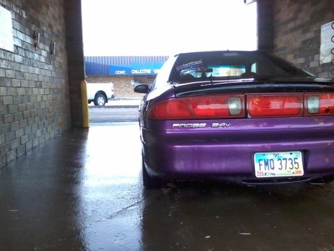 1995 Ford Probe - The rear of a purple 1995 Ford Probe is parked in a car wash bay. The license plate reads FMO 3735.