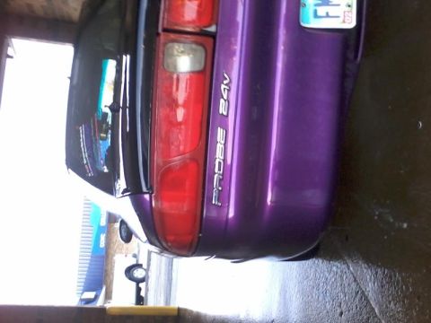 1995 Ford Probe - The rear passenger side of a purple 1995 Ford Probe is shown, with the "PROBE 24V" text visible on the taillight assembly. A license plate…