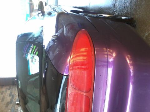 1995 Ford Probe - The rear passenger side of a purple 1995 Ford Probe is shown, with a close-up of the taillight and a sticker on the rear fender. The vehicl…