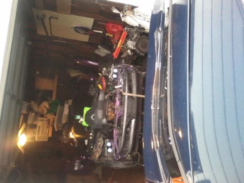 1995 Ford Probe - A dark-colored vehicle, possibly a Ford Probe, is parked inside a garage next to another dark blue vehicle. The vehicle on the left has its…
