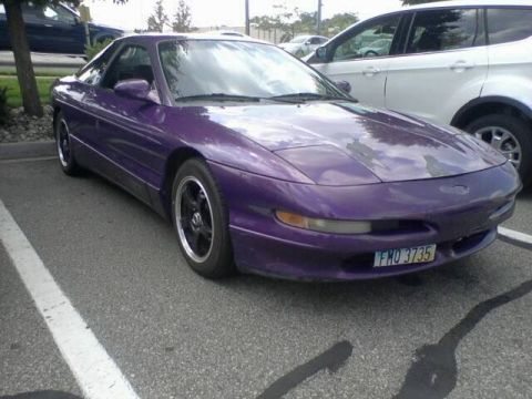 1995 Ford Probe - A purple 1995 Ford Probe is parked in a parking lot. The car is viewed from a 3/4 front angle, showing its sleek coupe body style and custo…