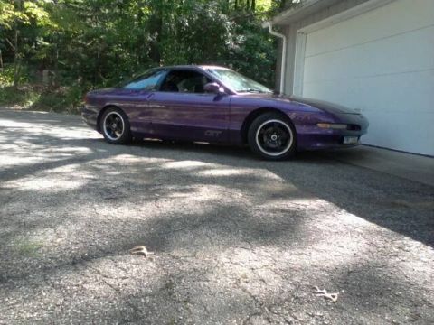 1995 Ford Probe - A purple 1995 Ford Probe is parked on a gravel driveway in front of a white garage door. The car is viewed from the side with the front qua…